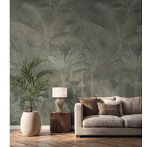 Papier peint intissé avec motif de palmiers dans un salon lumineux derrière un canapé crème, une lampe de table et une grande plante d'intérieur.