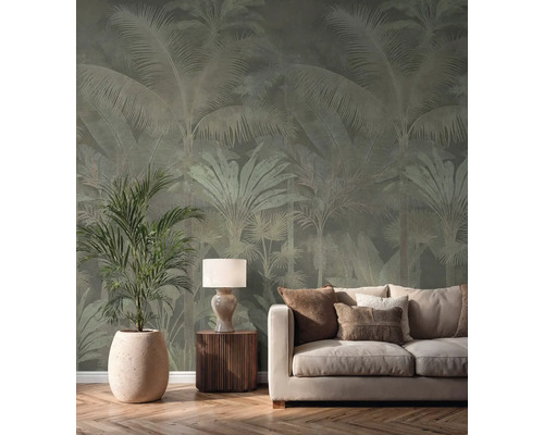 Papier peint intissé avec motif de palmiers dans un salon lumineux derrière un canapé crème, une lampe de table et une grande plante d'intérieur.