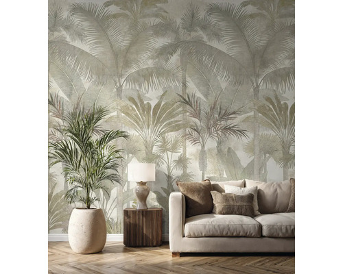 Papier peint intissé avec grand motif de palmiers dans un salon lumineux avec canapé beige, meubles en bois et une grande plante.