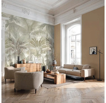 Salon lumineux avec papier peint panoramique motif palmiers, canapé, fauteuils, meubles en bois et parquet à chevrons.