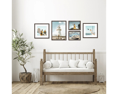 Décoration murale avec une sélection d'images encadrées au-dessus d'un canapé en bois