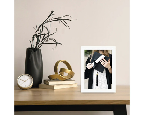 Nature morte décorative avec horloge, vase, sculpture, livres et une photo encadrée