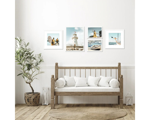 Mur décoratif avec des cadres représentant des scènes de vacances, au-dessus d'un banc en bois avec des coussins