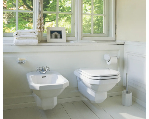 Badezimmer mit Bidet, Toilette und Badaccessoires vor einem Fenster