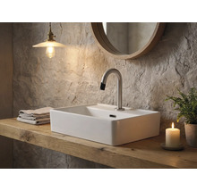 Badezimmer mit Aufsatzwaschbecken, Armatur, Spiegel, Handtüchern, Lampe, Kerze und Topfpflanze auf einem Holztisch