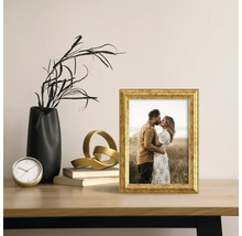 Cadre photo décoratif de couleur dorée sur une table avec d'autres objets de décoration