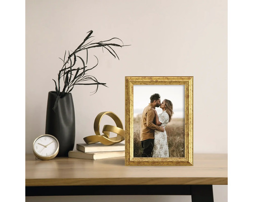 Scène décorative avec un cadre photo doré, un vase noir et une sculpture dorée