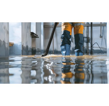 Person mit Nasssauger bei der Beseitigung von Wasser