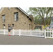 Clôture de jardin blanche devant une maison d'habitation.