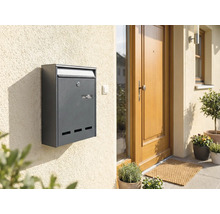 Boîte aux lettres anthracite sur un mur de maison à côté d'une porte d'entrée