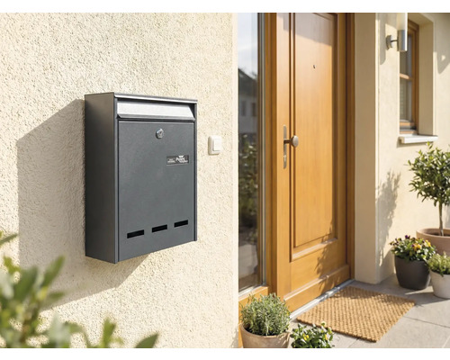 Boîte aux lettres anthracite sur un mur de maison à côté d'une porte d'entrée