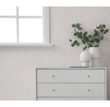 Heller Raum mat enger wäisser Fënster, enger heller Mauer an enger wäisser Kommod, dekoréiert mat Vasen an Eucalyptus-Zweigen.