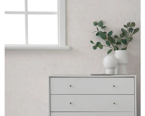 Heller Raum mat enger wäisser Fënster, enger heller Mauer an enger wäisser Kommod, dekoréiert mat Vasen an Eucalyptus-Zweigen.