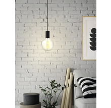 Lampe suspendue avec ampoule Edison devant un mur de briques