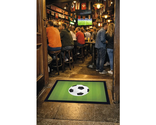 Fußmatte mit Fußballmotiv vor einer Bar