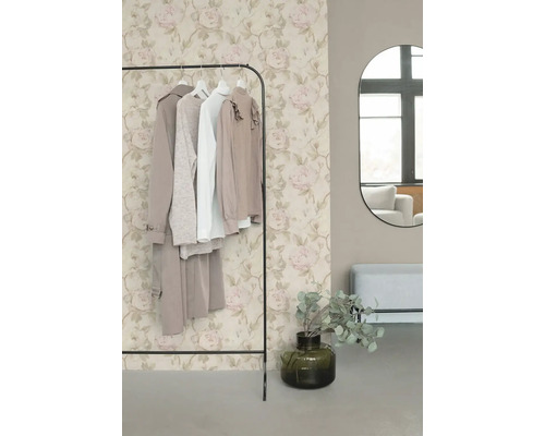 Papier peint intissé avec motif de roses romantique en beige et rose derrière un portant à vêtements dans un dressing moderne.