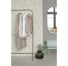 Pièce organisée et lumineuse avec papier peint intissé à motif floral, portant à vêtements en métal, miroir mural ovale et banc.