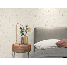 Helles Schlafzimmer mit floral gemusterter Tapete, grauem Polsterbett, rundem Nachttisch aus Holz und moderner Tischlampe aus Metall.