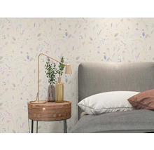 Vliestapete mit feinem floralem Muster in einem hellen Schlafzimmer mit grauem Polsterbett und hölzernem Nachttisch.