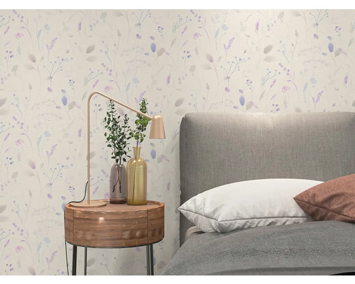 Vliestapete mit feinem floralem Muster in einem hellen Schlafzimmer mit grauem Polsterbett und hölzernem Nachttisch.
