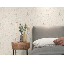 Helle Vliestapete mit feinem floralem Muster aus Gräsern und Blüten in einem modern eingerichteten Schlafzimmer mit grauem Bett und Holznachttisch.