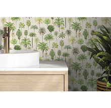 Papier peint intissé à motifs de palmiers dans une salle de bains lumineuse derrière un lavabo blanc et un meuble en bois.