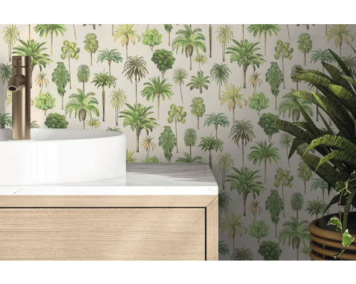 Papier peint intissé à motifs de palmiers dans une salle de bains lumineuse derrière un lavabo blanc et un meuble en bois.