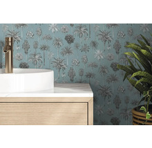 Papier peint à motif palmiers derrière une vasque blanche, robinet doré et meuble en bois dans une salle de bain moderne.