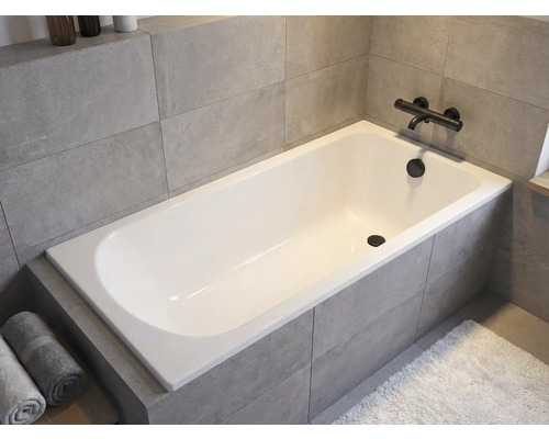 Baignoire encastrée dans une salle de bain avec robinetterie et serviettes