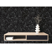 Moderne Inneneinrichtung mit Tapete im One-Line-Art-Design mit weißen Gesichtern auf schwarzem Grund. Davor ein Sideboard aus Holz mit Vase.