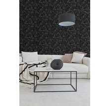 Wohnzimmer mit schwarzer Tapete mit weißen Gesichtern in Linienzeichnung, hellem Cordsofa und weißem Couchtisch mit schwarzem Metallgestell.