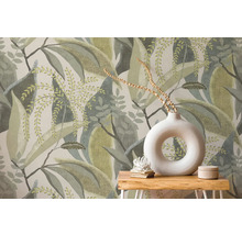 Papier peint intissé avec motif de grandes feuilles derrière une table en bois avec un vase rond blanc et de la décoration.