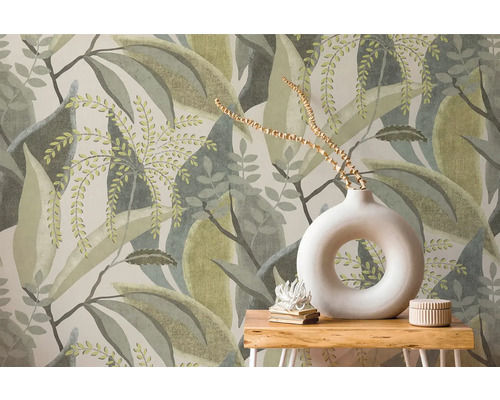 Papier peint intissé avec motif de grandes feuilles derrière une table en bois avec un vase rond blanc et de la décoration.