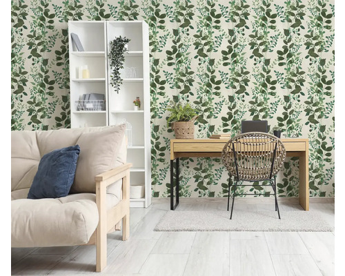 Hell gestalteter Raum mit botanischer Tapete mit grünem Blattmuster, Holzschreibtisch, Rattanstuhl und weißem Regal.