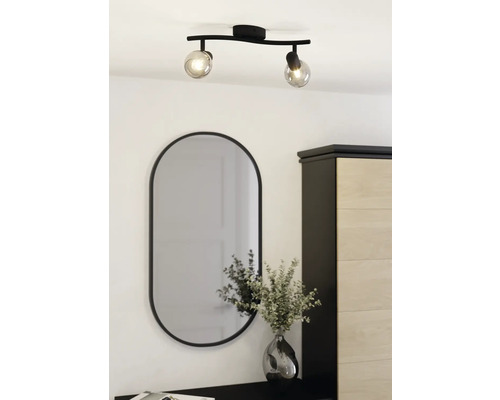 Plafonnier avec deux spots et miroir ovale au-dessus d'une commode