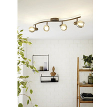 Plafonnier avec quatre spots et abat-jour en verre sur une barre incurvée.