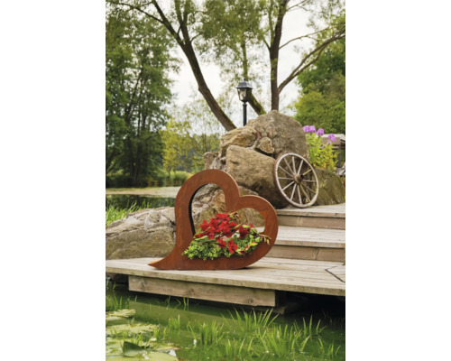 Dekoratives Herz aus Metall mit Blumen auf Holzsteg am Teich