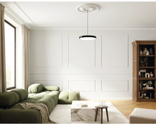 Salon avec canapé vert, table basse, bibliothèque et suspension