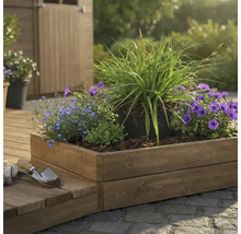 Jardinière en bois avec diverses plantes et outils de jardinage à l'extérieur.