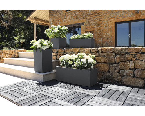 Extérieur de jardinières rectangulaires et carrées avec des fleurs devant un bâtiment.