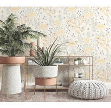 Dekoratives Interieur mit Zimmerpflanzen, Regal und Pouf vor einer floralen Tapete