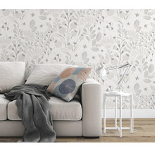 Wohnzimmer mit Sofa, Kissen, Decke, Tischlampe und Blumentapete