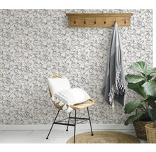 Pièce décorée avec une chaise, une serviette, une plante et un papier peint floral