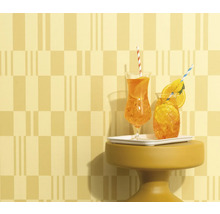 Deux boissons avec des pailles et des tranches d'orange sur une petite table devant un mur à motifs.