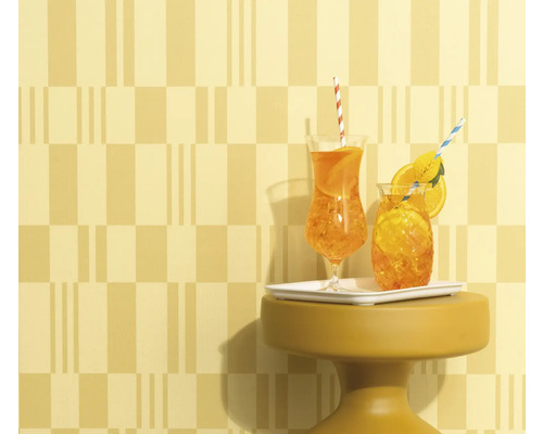 Deux boissons avec des pailles et des tranches d'orange sur une petite table devant un mur à motifs.