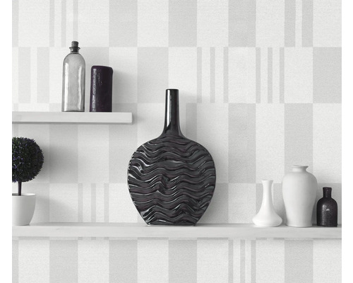Vases décoratifs sur étagères blanches devant un mur à motifs