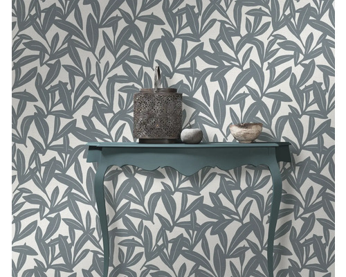 Intérieur décoratif avec une table, une lanterne et un mur avec du papier peint à motifs de feuilles.