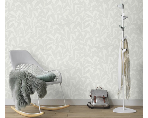 Vue d'une pièce avec papier peint à motifs de feuilles, fauteuil à bascule, portemanteau et sac