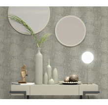 Scène décorative avec papier peint aspect cuir de crocodile, miroirs ronds, lampe de table et vases sur une commode