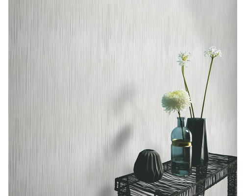 Papier peint clair avec motif à rayures verticales devant une table avec des vases et des fleurs